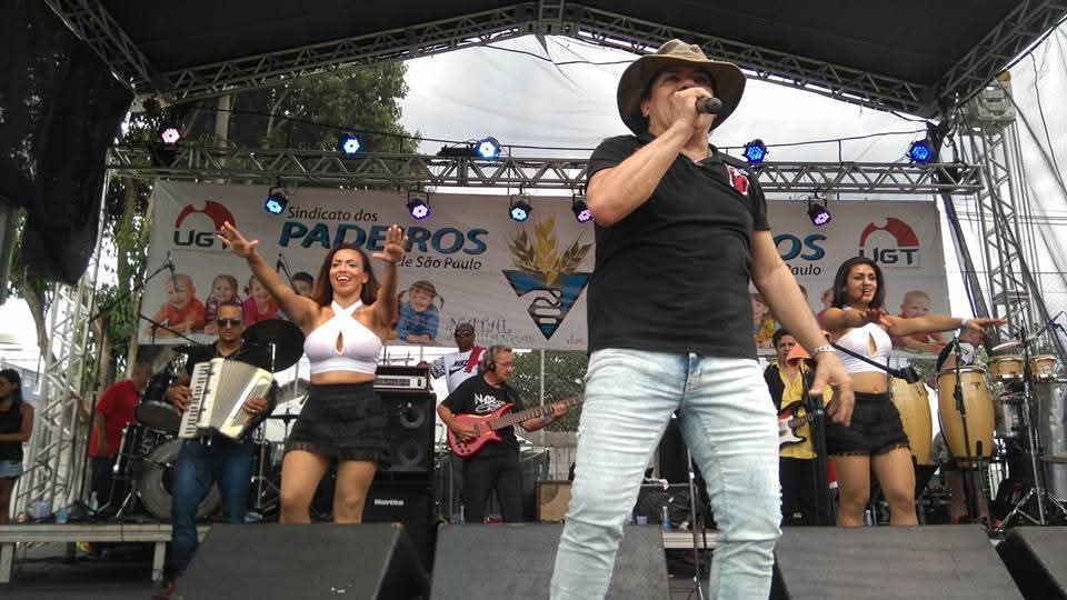 Tonyan cantando com banda e dançarinas em palco ao ar livre